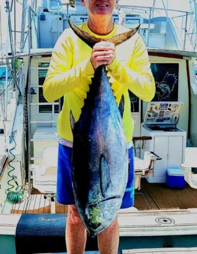 A man holding a fish that's almost as tall as he is.