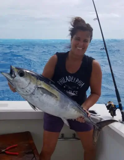 Woman holding a very large fish that she caught.