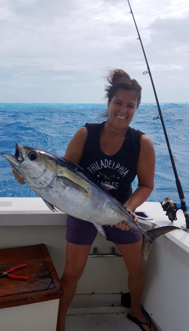 Woman holding a large Amberjack fish that she caught.